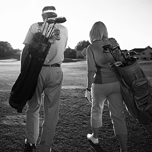 Elderly couple walking on golf course with golf bags
