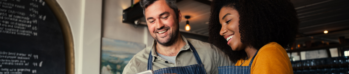 Happy manager and waitress looking at tablet.