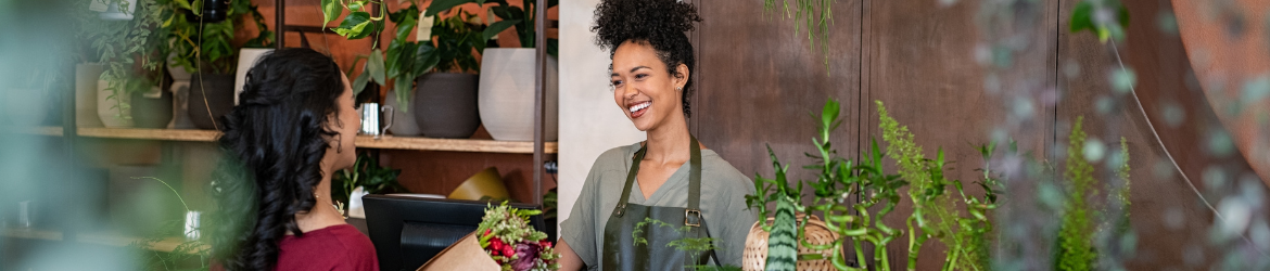 Happy flower shop employee interacting with customer.