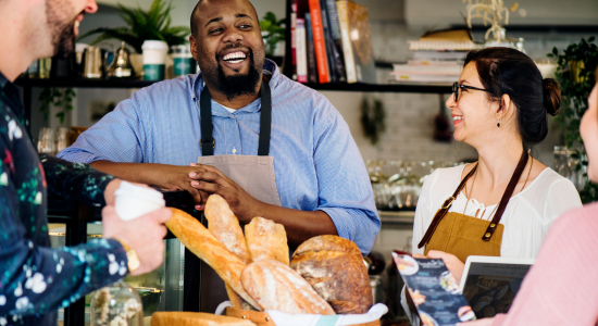 Employees and customers at coffee shop interacting with each other.