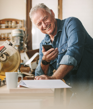 Happy man looking at phone in workshop.