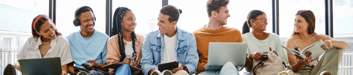 Group of young adults sitting with laptops and smiling.