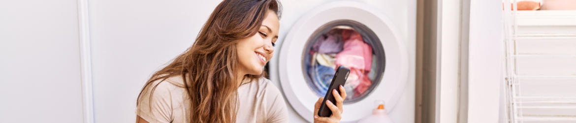 Woman looking at phone in laundry room.