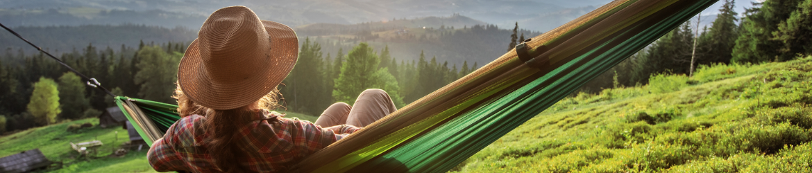 Woman relaxing in hammock on a hill. 