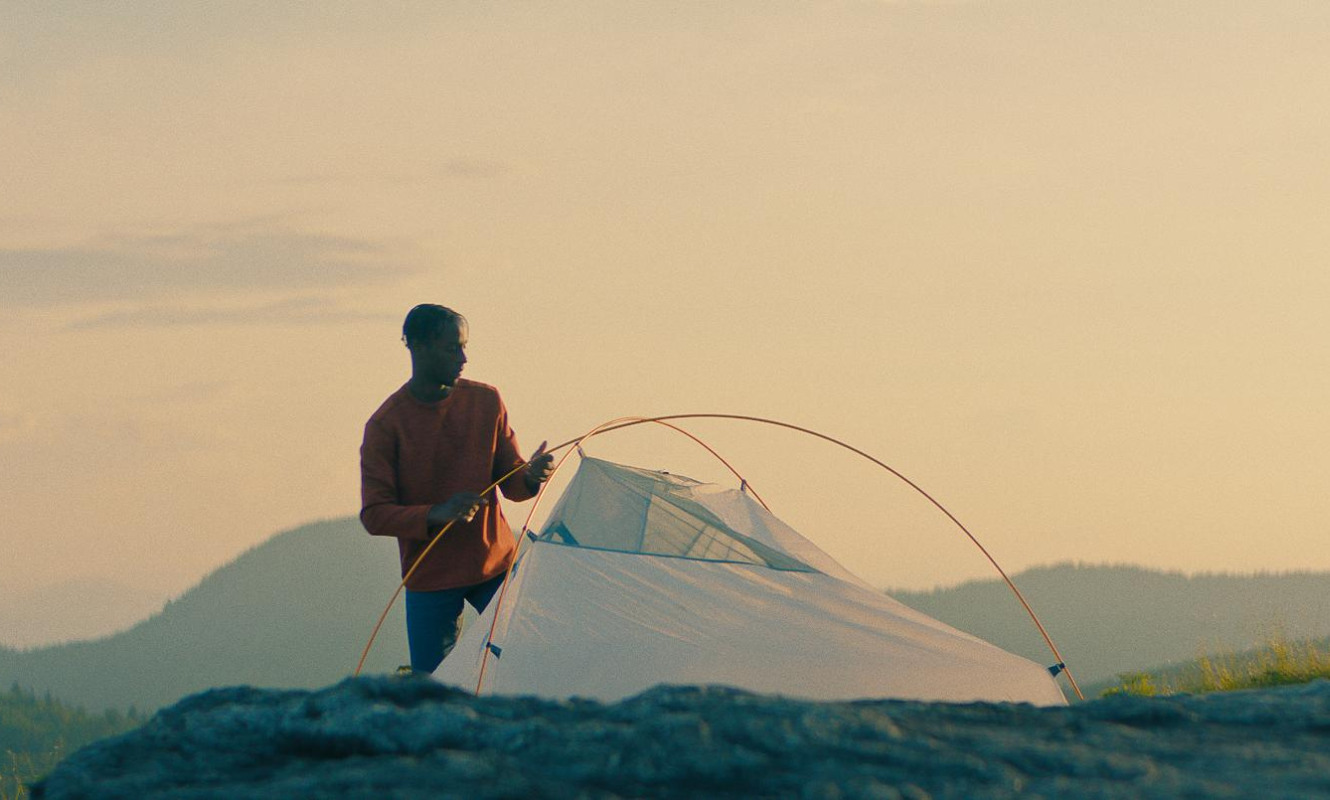 Man setting up a tent on mountain top.