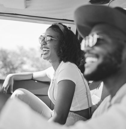 Man and woman smiling while driving in car.