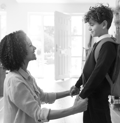 Mother holding son's hands as he gets ready for school