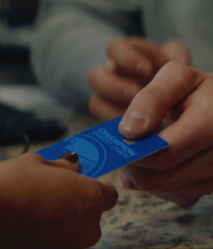 Hands holding blue Champion Credit Union card.