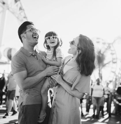 Parents holding daughter happy at amusement park. 