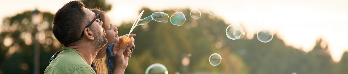 Father and Daughter blowing bubbles outside.