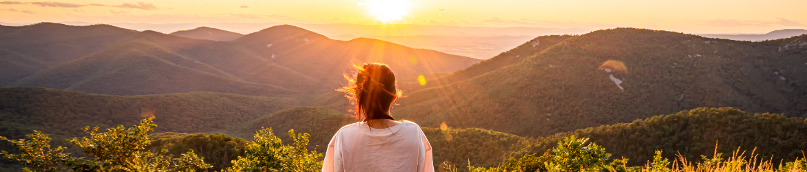 Woman viewing sunset over blue ridge mountains.