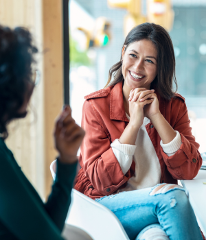 Woman with folded hands smiling with person. 