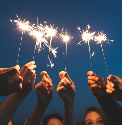 Group of hands holding up sparklers.