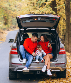 Family in back of open car trunk in the fall.