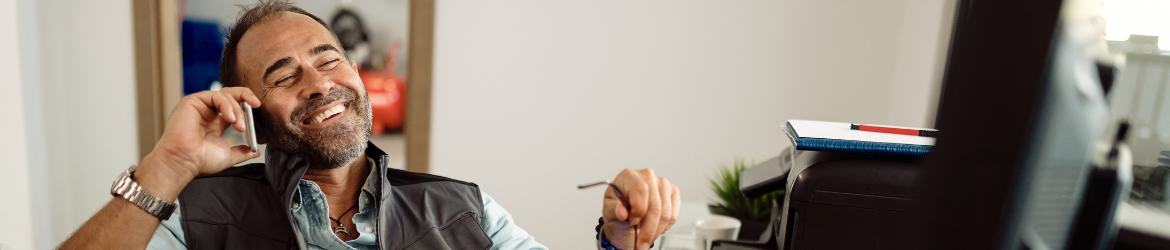 Happy man sitting in office chair on the phone.